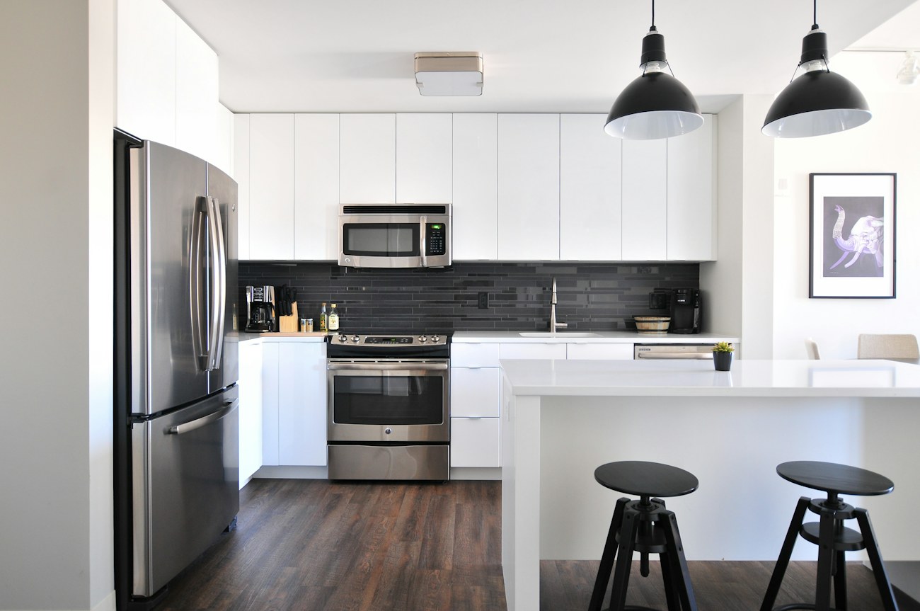 A bright kitchen with white cabinets and clear worktops